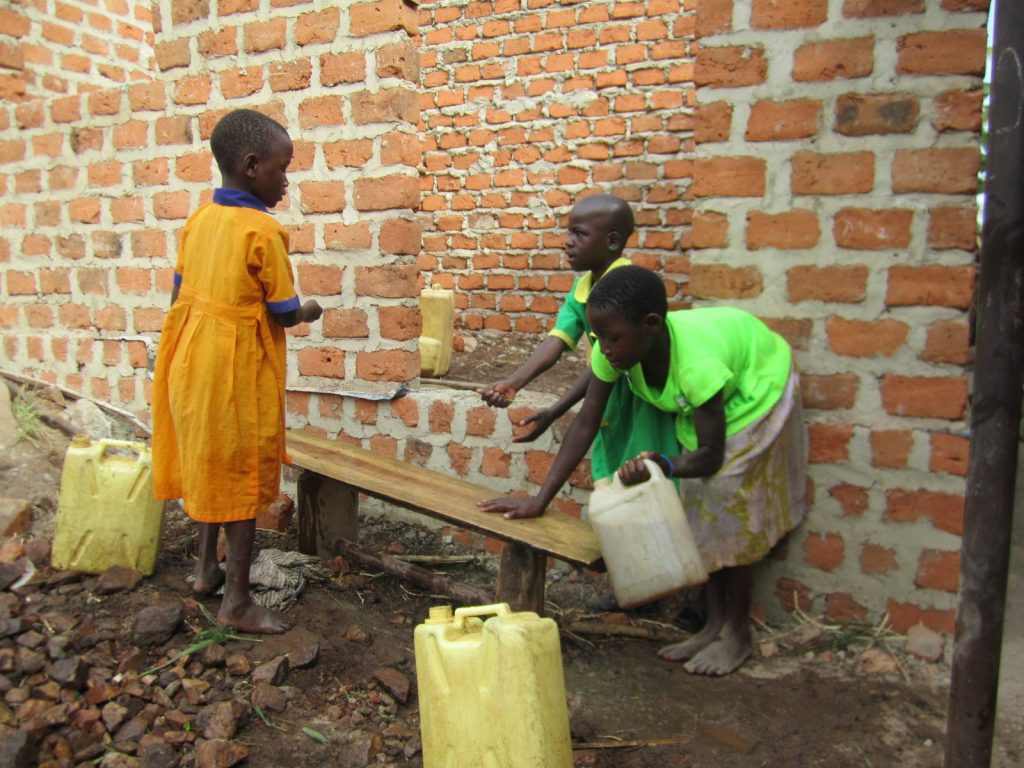 Kinder holen Wasser an der Schulwand