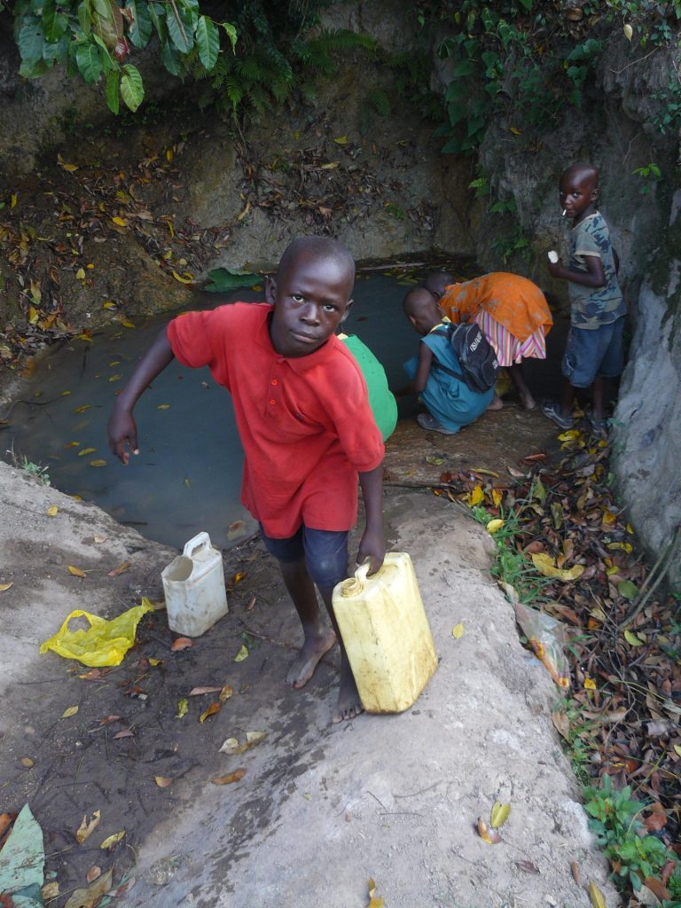 Junge holt Wasser an der Quelle