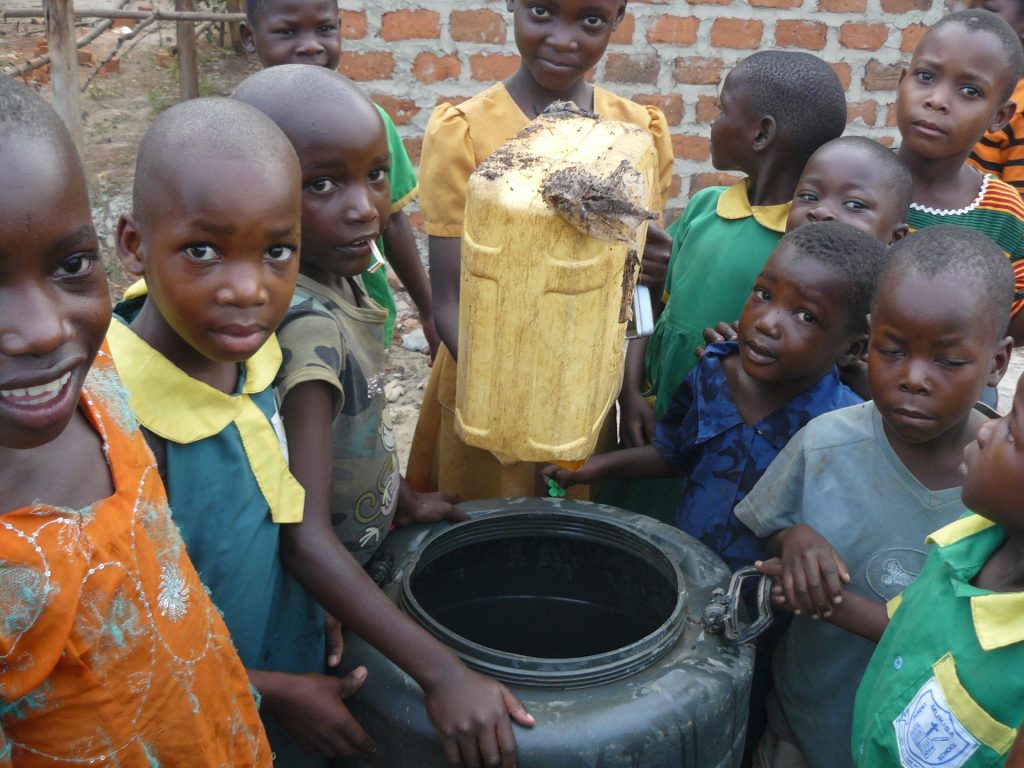 Kinder um eine Wassertonne