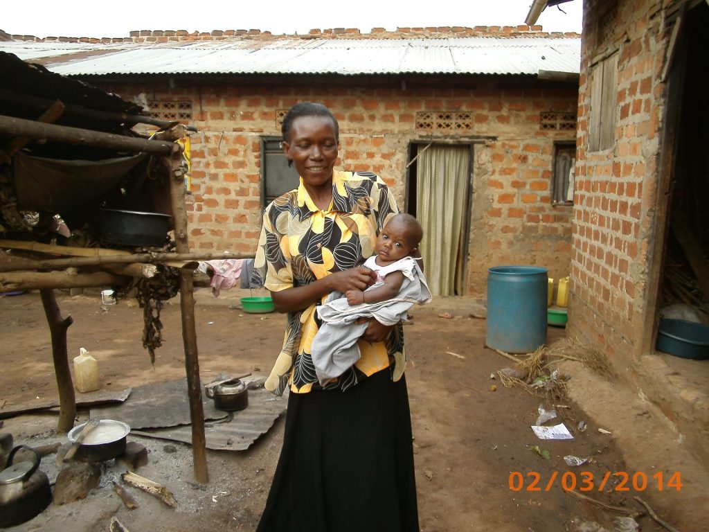 Frau mit Baby vor ihrem Haus